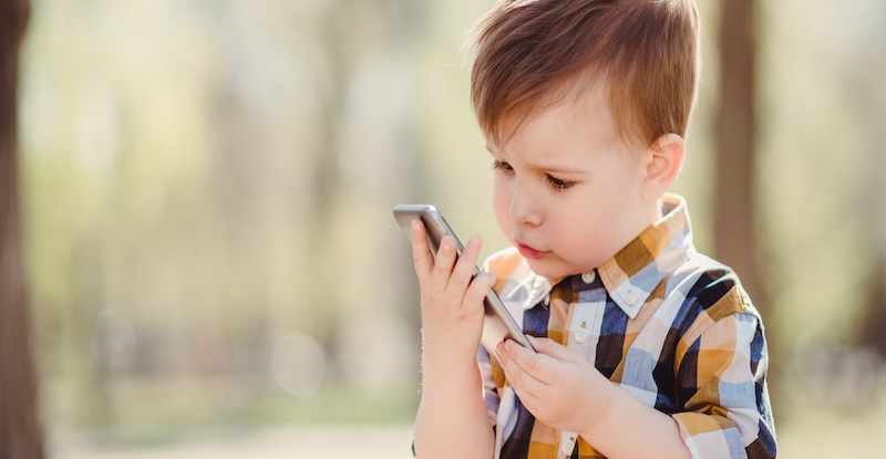 cute boy speaks by mobile phone in the park