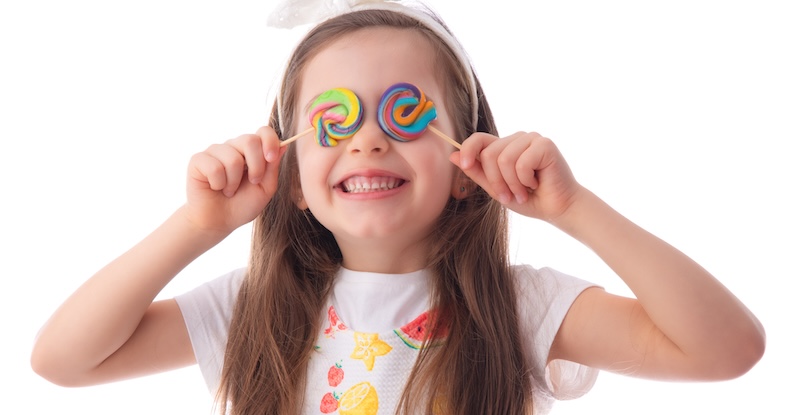 Little kid eating lollipop. Happy beautiful girl with candy isolated on white background